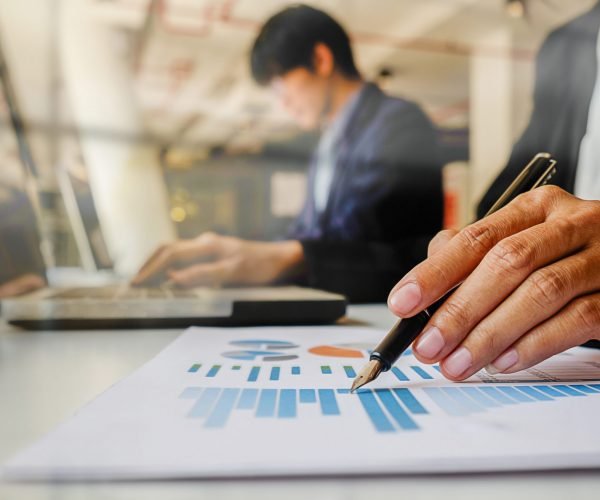 Business concept. Business people discussing the charts and graphs showing the results of their successful teamwork. Selective focus.